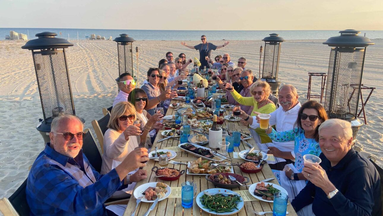 Family and friends gathered together for a meal by the beach.